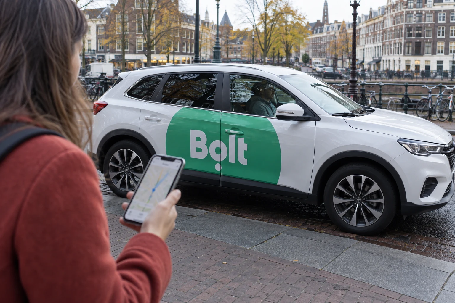 Reiziger met smartphone naast een witte Bolt-taxi aan een Amsterdamse gracht